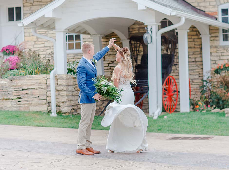 Bride and groom spin in a dance outside the Mayowood Stone Barn wedding and event venue in Rochester